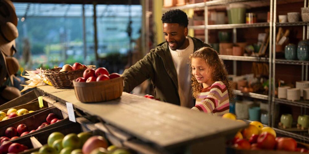 father and daughter shopping at a fruit stand