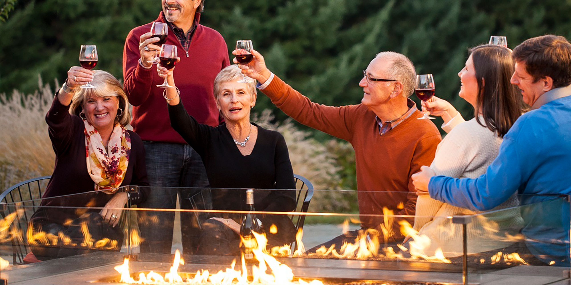 group of friends drinking wine near a firepit