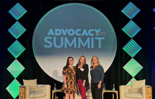 three ladies standing on stage at a conference