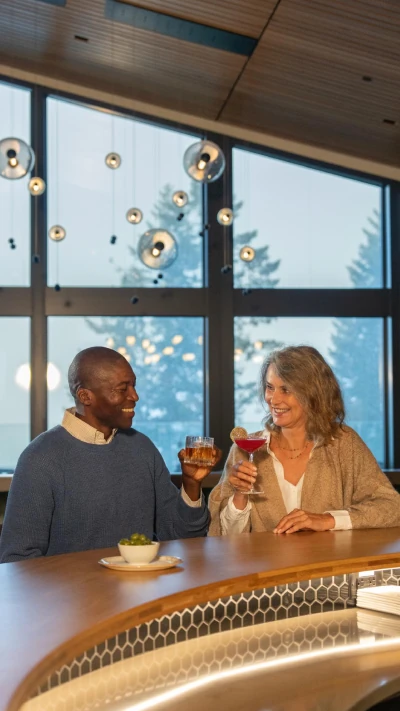 A couple toasting cocktails at a bar